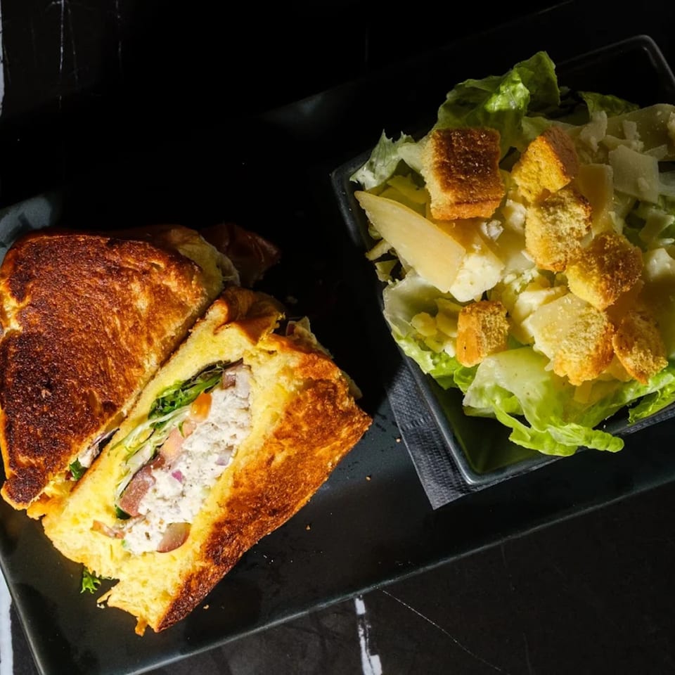 Grilled sandwich with chicken salad and a side of Caesar salad with croutons and parmesan.